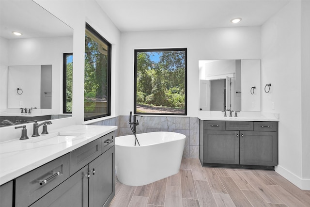 bathroom featuring hardwood / wood-style flooring, vanity, a wealth of natural light, and a bathtub