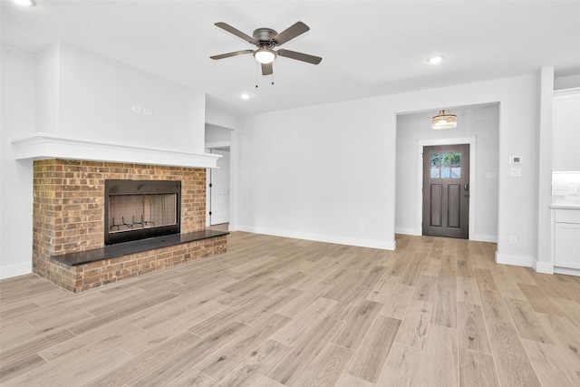 651 Paradise Dr, Coldspring, TX 77331 - unfurnished living room featuring a brick fireplace, light wood finished floors, a ceiling fan, baseboards, and recessed lighting