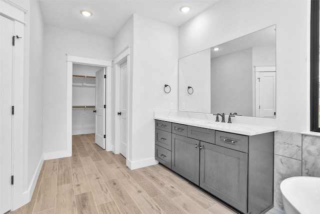651 Paradise Dr, Coldspring, TX 77331 - bathroom with wood finished floors, a freestanding tub, vanity, baseboards, and a walk in closet