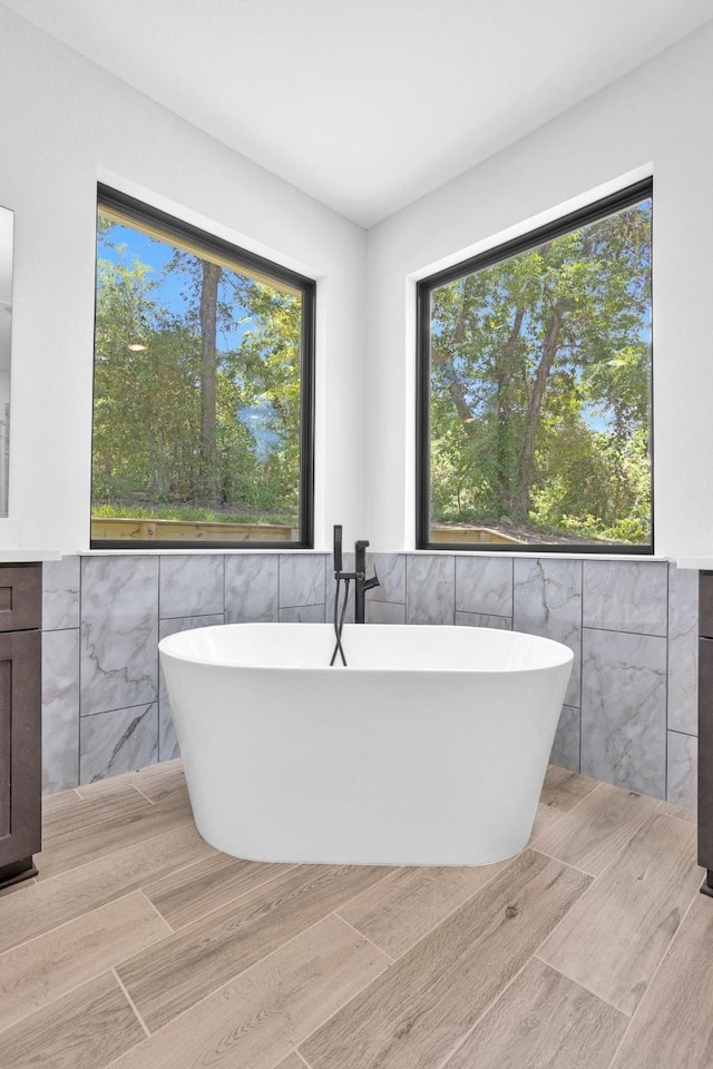 651 Paradise Dr, Coldspring, TX 77331 - full bathroom with tile walls, a soaking tub, wood finished floors, and wainscoting