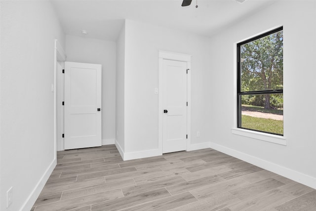 unfurnished bedroom featuring ceiling fan, light hardwood / wood-style floors, and multiple windows