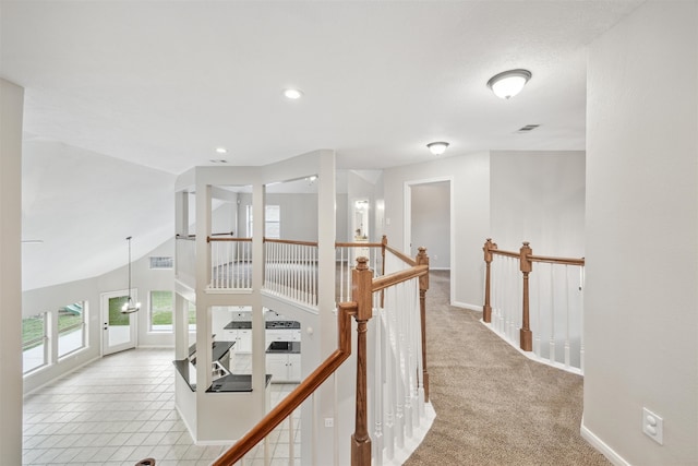 corridor with light colored carpet and vaulted ceiling