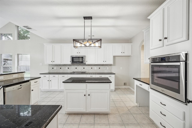 kitchen with pendant lighting, backsplash, light tile floors, a center island, and appliances with stainless steel finishes