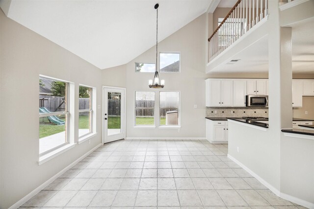 kitchen featuring high vaulted ceiling, decorative light fixtures, white cabinetry, and a notable chandelier