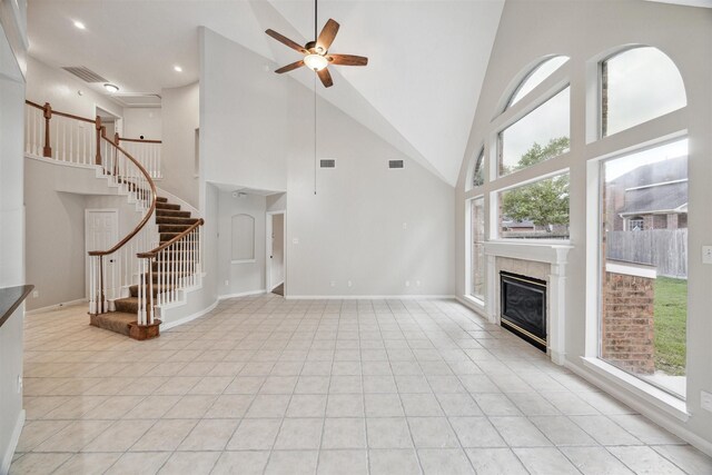 unfurnished living room featuring high vaulted ceiling, ceiling fan, and a premium fireplace