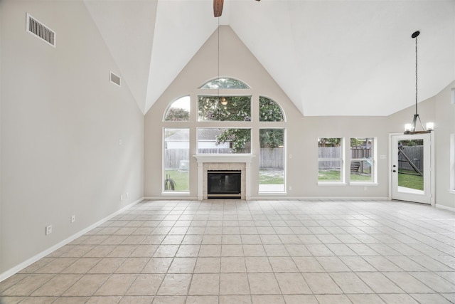 unfurnished living room featuring high vaulted ceiling, a tiled fireplace, ceiling fan with notable chandelier, and light tile floors