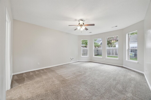 empty room featuring a healthy amount of sunlight, carpet floors, and ceiling fan