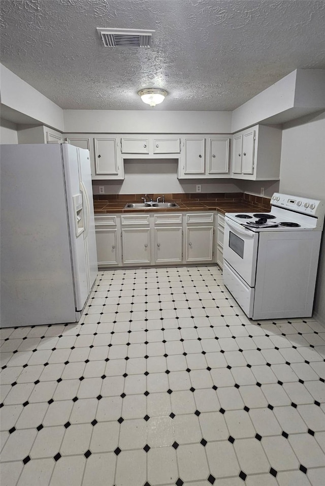 kitchen with white cabinets, white appliances, sink, and a textured ceiling