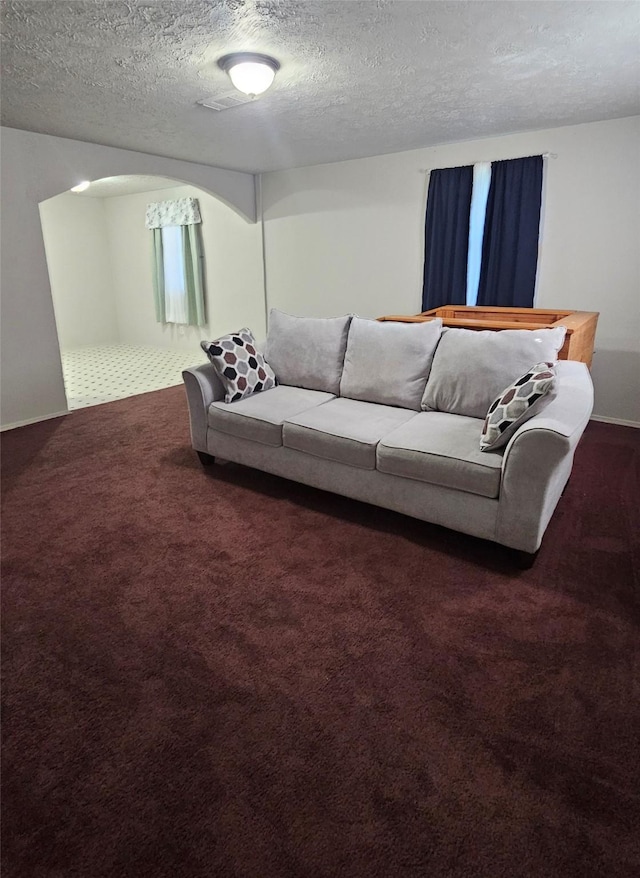 living room featuring a textured ceiling and dark carpet