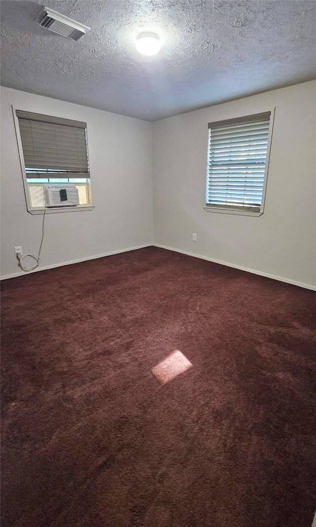 spare room featuring cooling unit, carpet, and a textured ceiling