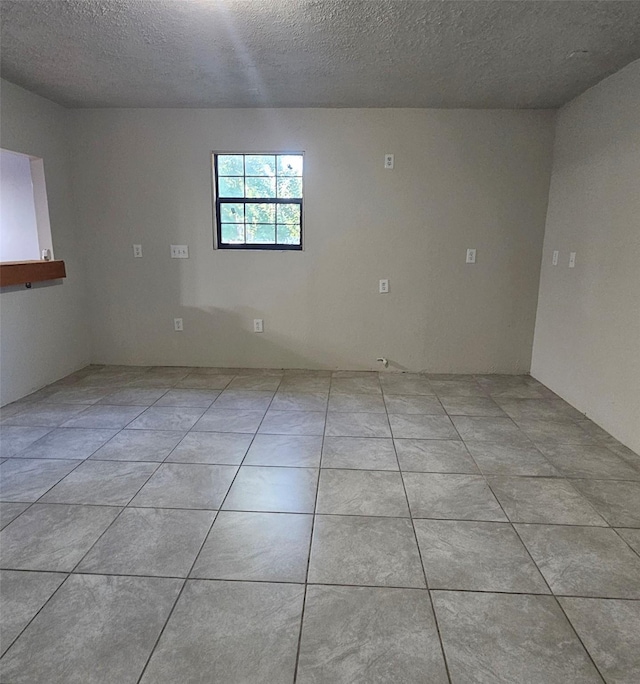 tiled spare room featuring a textured ceiling