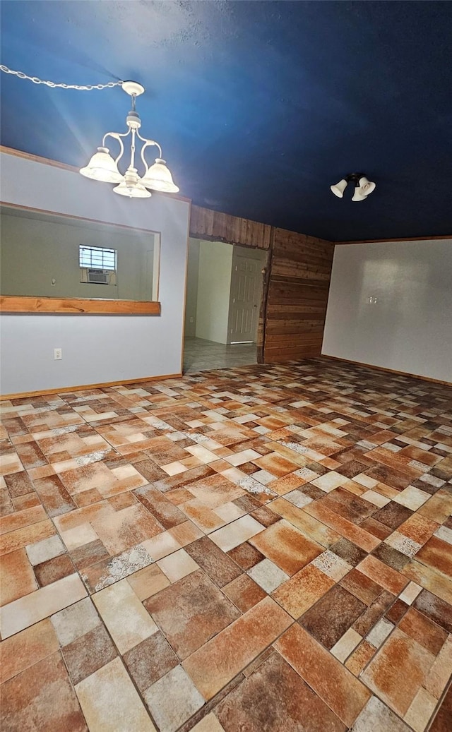 empty room featuring a chandelier and wood walls