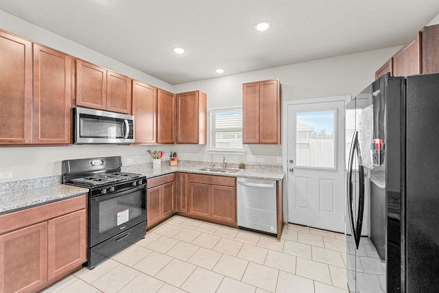 kitchen featuring sink, light tile patterned floors, light stone countertops, and stainless steel appliances