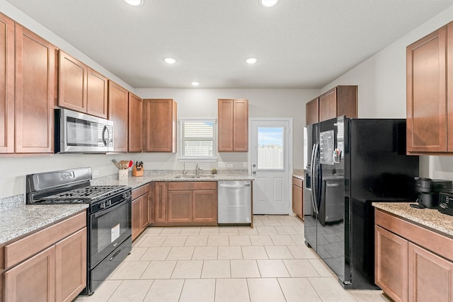 kitchen featuring light tile patterned flooring, sink, light stone countertops, and black appliances