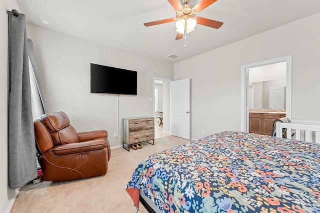 bedroom featuring ceiling fan, light colored carpet, and ensuite bathroom