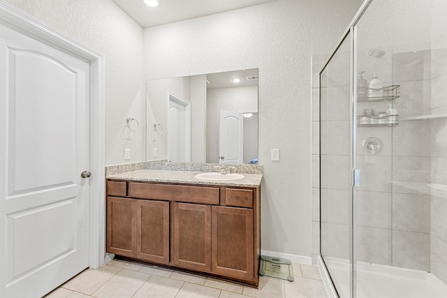 bathroom with tile patterned floors, a shower with door, and vanity