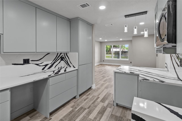 kitchen featuring backsplash, light hardwood / wood-style floors, decorative light fixtures, and gray cabinetry