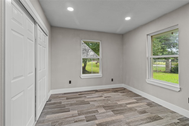 unfurnished bedroom featuring multiple windows, hardwood / wood-style flooring, and a closet