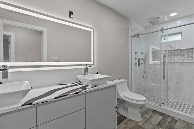 bathroom featuring dual bowl vanity, an enclosed shower, hardwood / wood-style flooring, and toilet