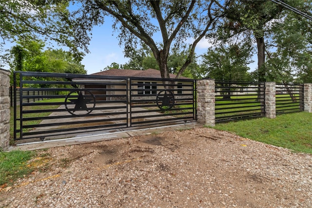 view of gate with a lawn and a rural view