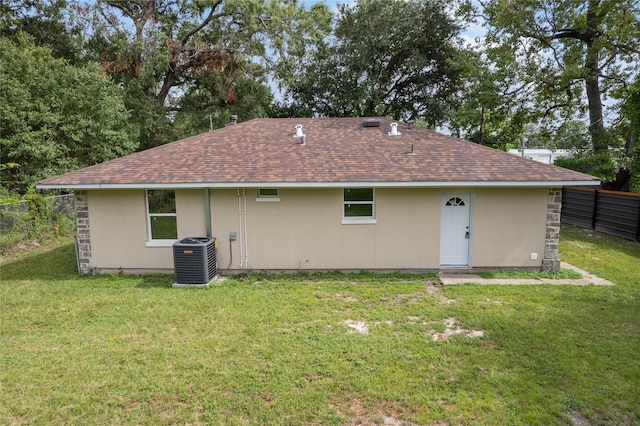 rear view of house with central AC unit and a yard