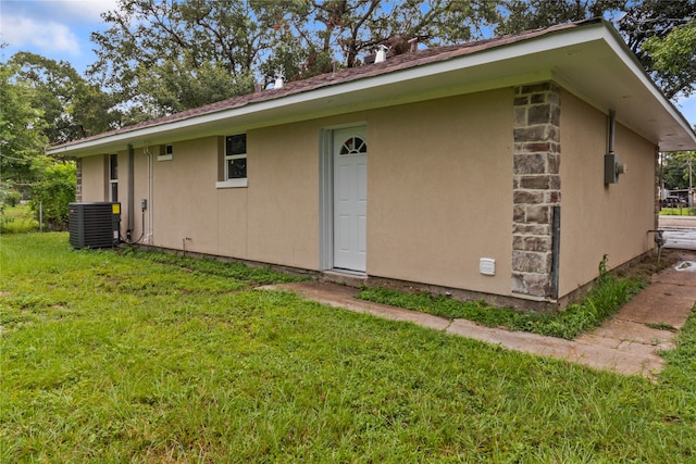 rear view of house with central AC and a lawn