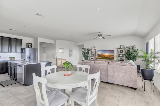 tiled dining area featuring ceiling fan, sink, and vaulted ceiling