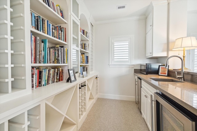 interior space with white cabinets, light carpet, wine cooler, sink, and ornamental molding