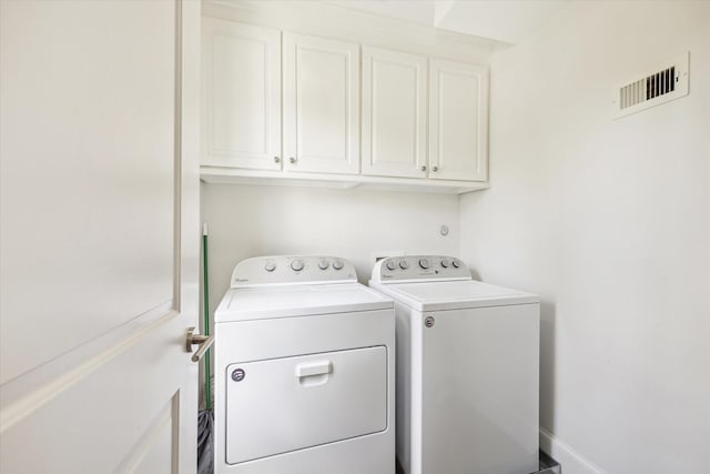 clothes washing area with washing machine and dryer and cabinets