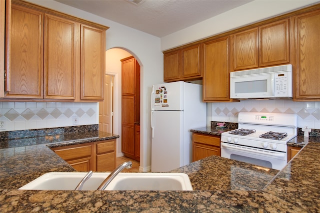 kitchen featuring sink, white appliances, and backsplash