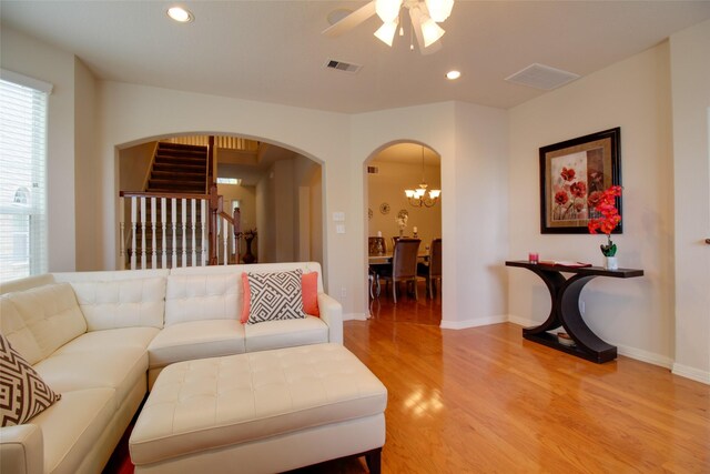 living room featuring ceiling fan with notable chandelier and hardwood / wood-style floors