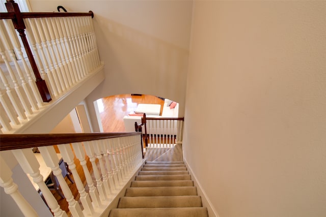 staircase with a high ceiling and hardwood / wood-style floors