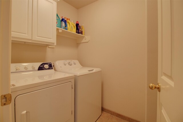 clothes washing area with cabinets, light tile flooring, and independent washer and dryer