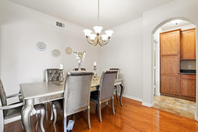 dining space with a notable chandelier and light hardwood / wood-style floors