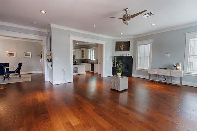 unfurnished living room with ceiling fan, ornamental molding, and dark wood-type flooring