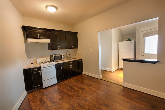 kitchen featuring dark brown cabinets, sink, dark hardwood / wood-style flooring, and white appliances