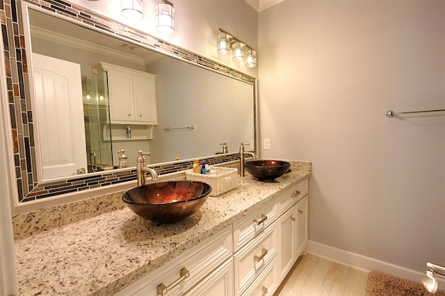 bathroom featuring double vanity, crown molding, and hardwood / wood-style floors