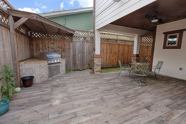 wooden deck featuring area for grilling, a patio, an outdoor kitchen, and ceiling fan