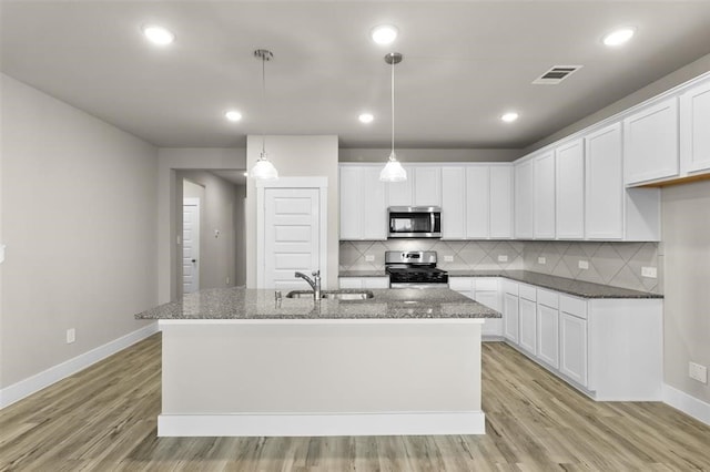 kitchen with stainless steel appliances, a sink, light wood-style floors, baseboards, and tasteful backsplash