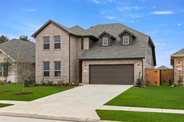 view of front of house with brick siding, concrete driveway, a front lawn, and fence