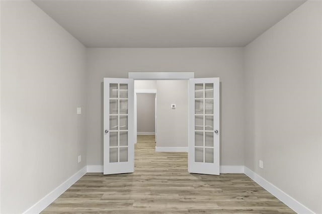 spare room featuring wood finished floors, french doors, and baseboards