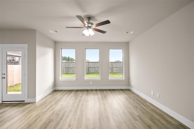 empty room featuring baseboards, visible vents, and a healthy amount of sunlight