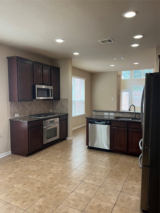 kitchen with dark brown cabinetry, appliances with stainless steel finishes, tasteful backsplash, and light tile patterned floors