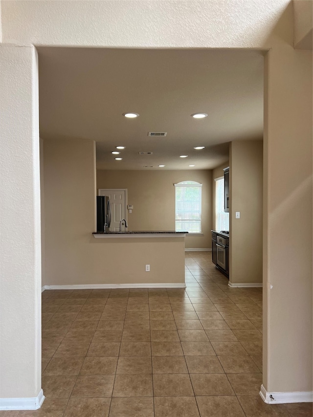 interior space featuring sink, kitchen peninsula, light tile patterned floors, and refrigerator