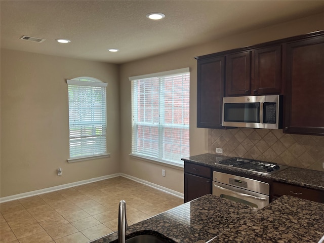 kitchen with plenty of natural light, decorative backsplash, appliances with stainless steel finishes, and light tile patterned floors