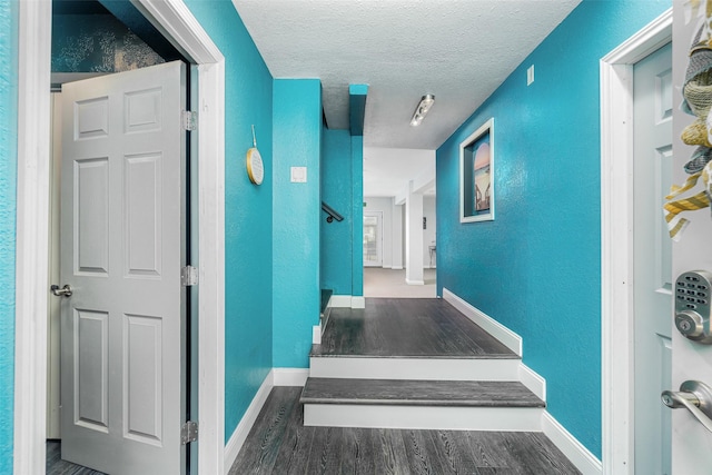 corridor featuring a textured ceiling and dark wood-type flooring