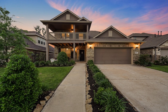 view of front facade with a lawn, a balcony, and a garage