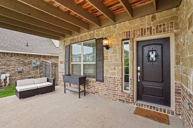 property entrance with stone siding, brick siding, a patio, and outdoor lounge area