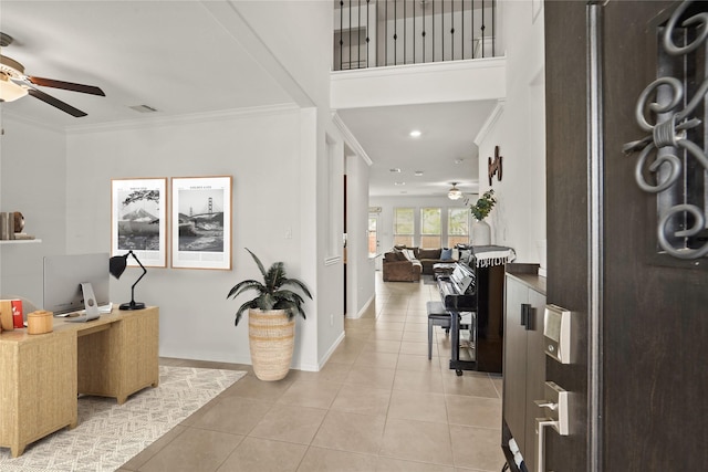 tiled foyer entrance with ceiling fan and crown molding