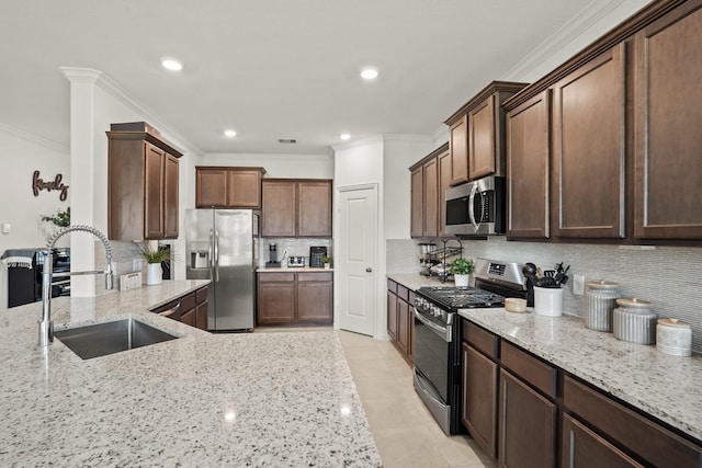 kitchen with appliances with stainless steel finishes, a sink, light stone countertops, crown molding, and backsplash